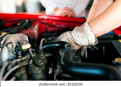 car mechanic in his repair shop standing next to the car - close-up of the engine - Powered by Shutterstock