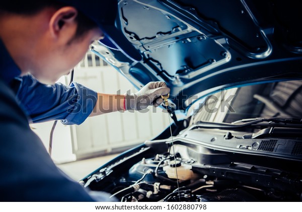 Car mechanic holding checking gear oil to\
maintenance vehicle by customer claim order in auto repair shop\
garage. Engine repair service. People occupation and business job.\
Automobile technician