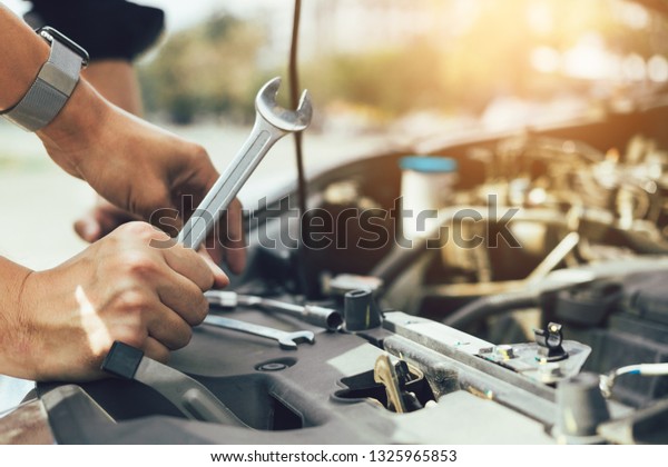 Car mechanic is holding a wrench ready to\
check the engine and\
maintenance.
