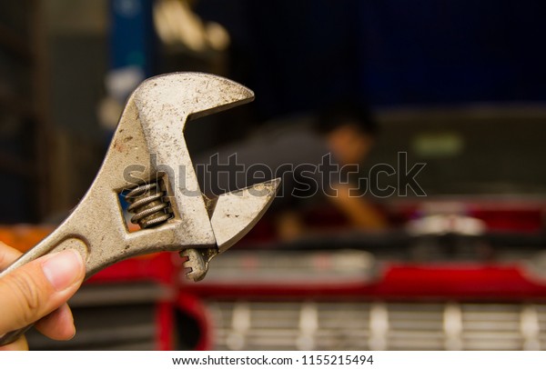 A car mechanic is holding a wrench to remove the\
car\'s parts.
