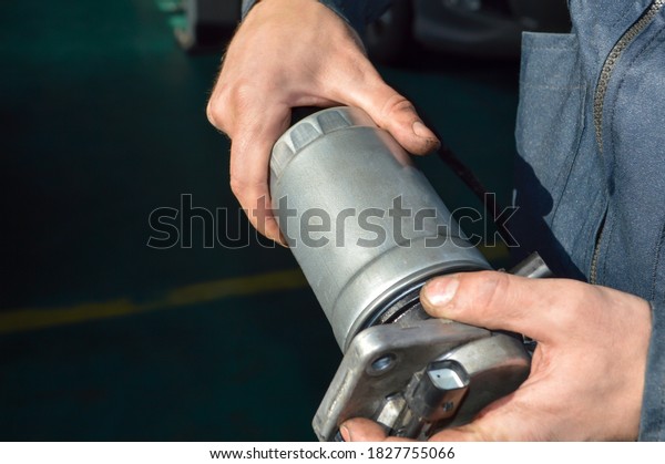 A car mechanic holds a fuel filter from a diesel\
internal combustion engine