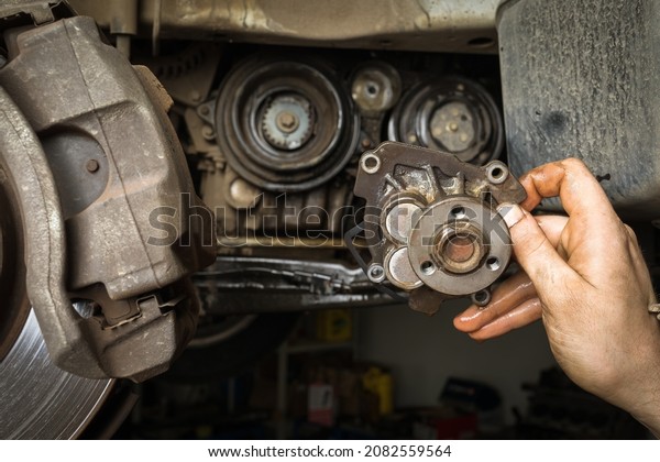 The car mechanic holds in his hand an old removed
car engine water pump