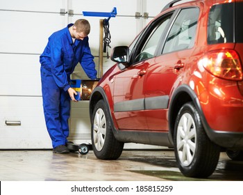 Car Mechanic Inspecting Headlight Lamp Of Automobile At Repair Service Station