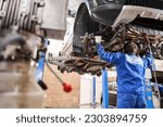 Car mechanic inspecting car steering rod and repair suspension detail. Lifted automobile at repair service station. replacement of ferrule and leverage
