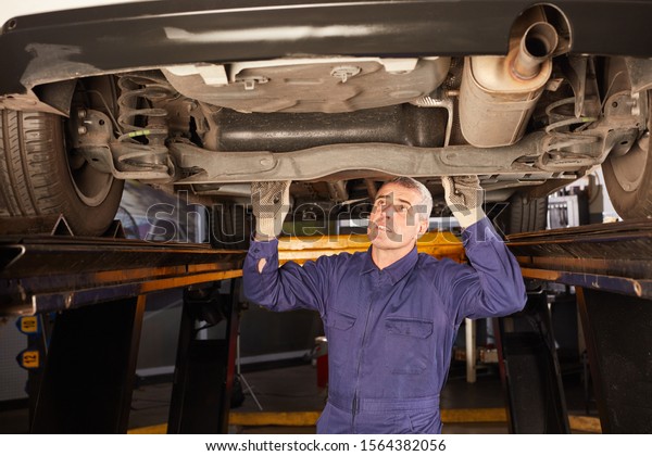 Car mechanic at the inspection checks\
underbody protection of the car for\
corrosion