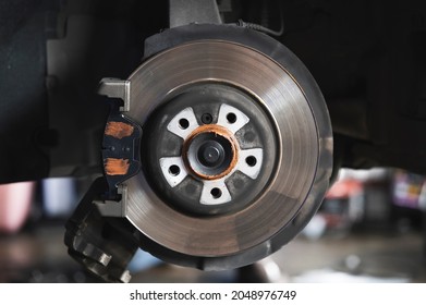 Car mechanic install front brake pads and rotors.