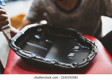 Car Mechanic Installing An RTV Silicone Liquid Gasket On The Oil Pan Flange.