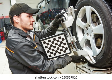 Car Mechanic Installing Sensor During Suspension Adjustment And Automobile Wheel Alignment Work At Repair Service Station