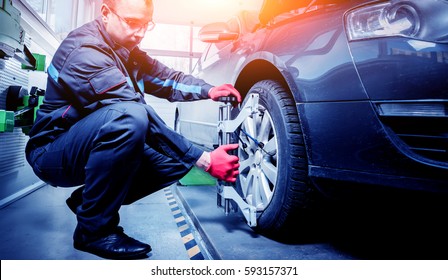 Car mechanic installing sensor during suspension adjustment. Wheel alignment work at repair service station - Powered by Shutterstock