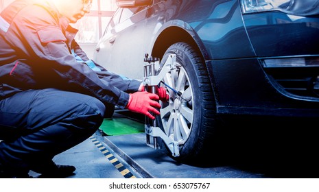 Car Mechanic Installing Sensor During Suspension Adjustment. Wheel Alignment Work At Repair Service Station