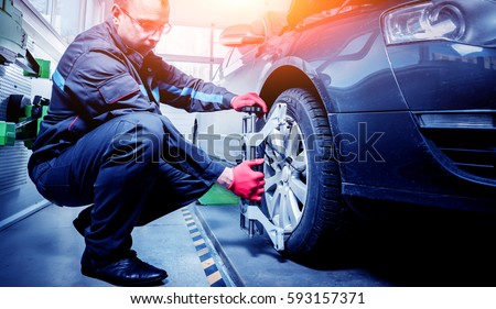 Car mechanic installing sensor during suspension adjustment. Wheel alignment work at repair service station