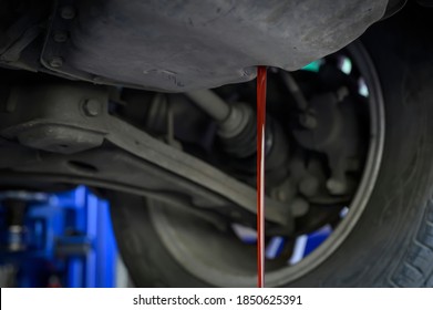 Car mechanic loosen the oil drain plug. Then let the used automatic transmission oil flow out of the oil pan. - Shutterstock ID 1850625391