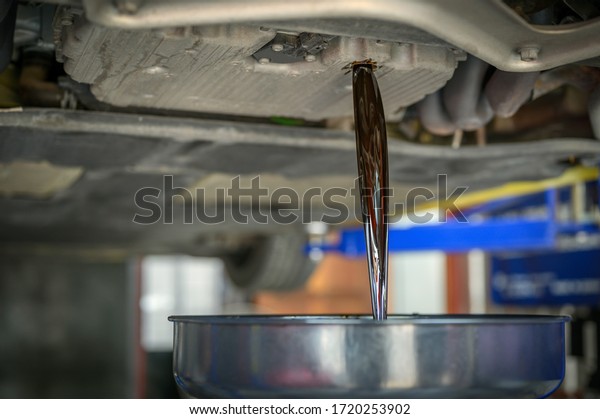 The car mechanic\
loosen the oil drain plug. Then let the used engine oil flow out of\
the engine oil pan.