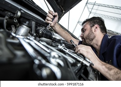 Car Mechanic Man At The Garage Fixing The Engine