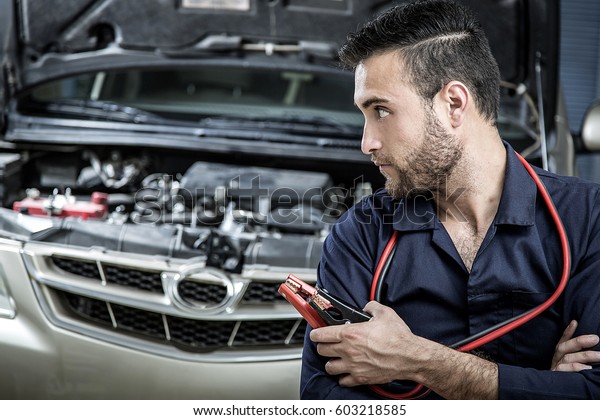 Car mechanic\
man at the garage fixing the\
engine