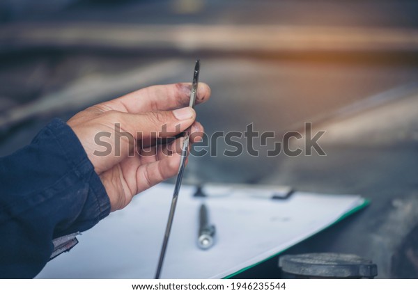 Car Mechanic man hand checking dipstick engine oil\
car mechanical on site service. Close up hand man check engine oil\
level Locate dipstick, wipe clean, check dipstick level before fill\
up engine oil