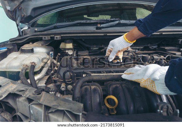 Car Mechanic man hand checking dipstick engine oil\
car mechanical on site service. Close up hand man check engine oil\
level Locate dipstick, wipe clean, check dipstick level before fill\
up engine oil