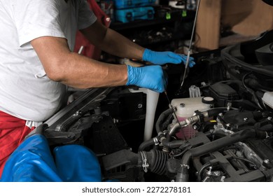 Car mechanic man wearing blue rubber gloves fixing vehicle engine from open hood car in auto repair shop, repairman checking car problem in garage - Powered by Shutterstock