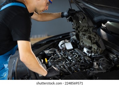 Car mechanic noting repair parts during open car hood engine repair at garage. Unrecognizable mechanic man open a car hood and check up the engine. Overheating of a car engine. Motor with open hood. - Powered by Shutterstock