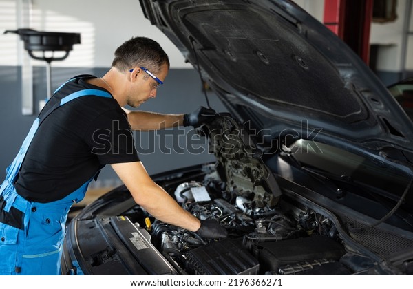Car\
mechanic noting repair parts during open car hood engine repair at\
garage. Mechanic man open a car hood and check up the engine.\
Overheating of a car engine. Motor with open\
hood.