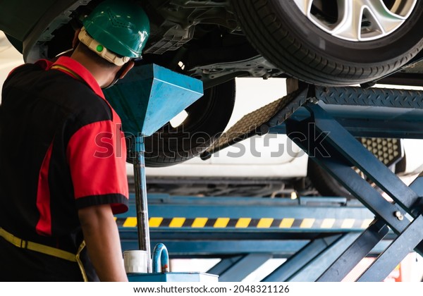 The car with mechanic oil change in the car\
service shop and employee on\
work.