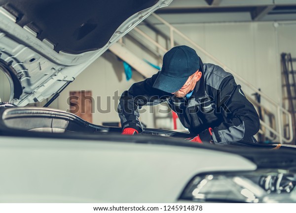 Car Mechanic on Duty. Caucasian Auto\
Service Worker Looking Under Vehicle Hood For Potential Issues.\
Automotive Industry.\
\

