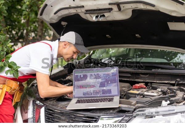 Car mechanic open\
hood to repair and check car problem system by laptop for\
maintenance and fixed in\
garage