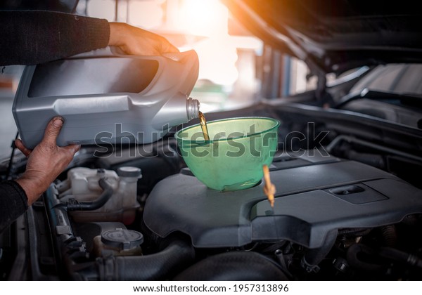 Car\
mechanic open car hood repairs  checking oil motor level for refill\
new oil in car garage service and\
maintenance.