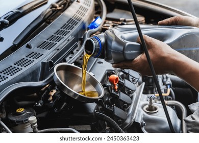 Car mechanic pouring engine oil into vehicle during doing car maintenance in garage - Powered by Shutterstock