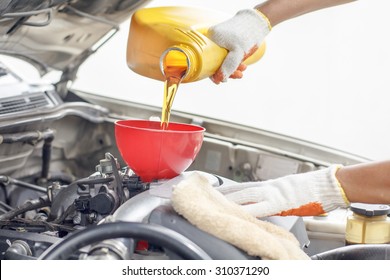 Car mechanic pouring new oil to engine.