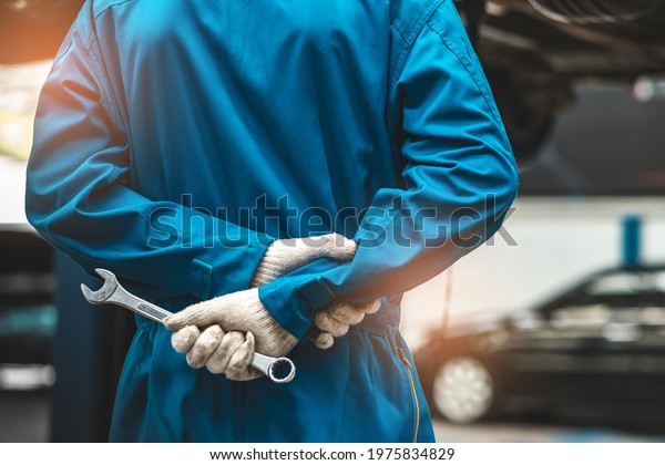 Car Mechanic Ready For Work. Auto
Mechanic with Large Wrench in Hands. Ideas How to Fix the
Problem.Male mechanics at the garage fixing a car.Closed up focus
.