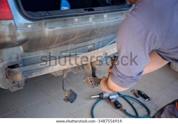 Car mechanic removing old tow hook with his\
hands. Car repair concept