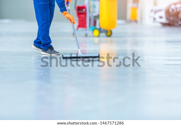 Car mechanic repair service center cleaning using\
mops to roll water from the epoxy floor. In the car repair service\
center.