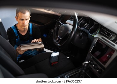 Car mechanic repair service and checking car engine by diagnostics software on tablet computer. Expertise mechanic working in automobile repair garage.