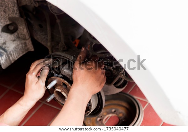 Car\
mechanic repairing car disk brake on the\
garage