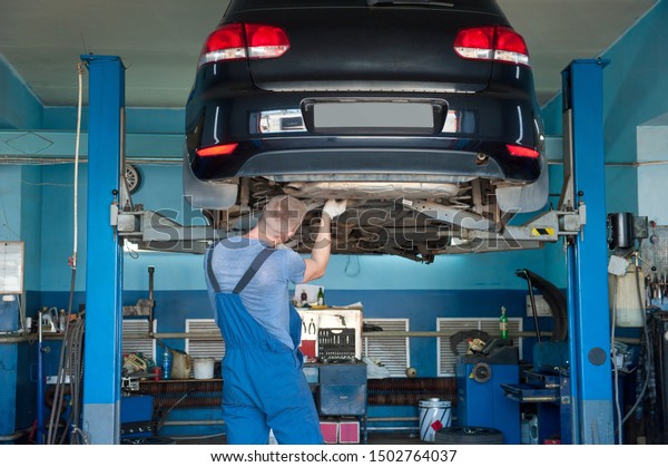 Car\
mechanic repairs a car chassis at a car\
service