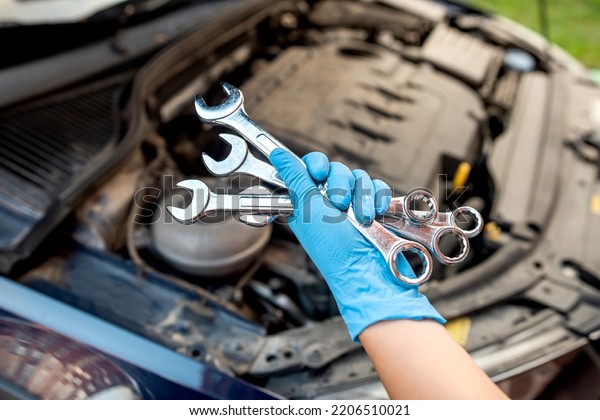 car mechanic repairs a car\
engine in a car workshop with a wrench. car maintenance. repair\
services.