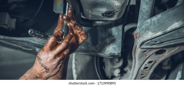 A car mechanic repairs a car at a car repair shop with a turnkey. close-up on hands