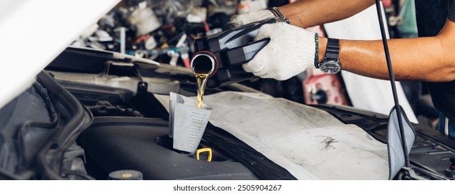 Car mechanic replacing and pouring fresh oil into engine at maintenance repair service station, Mechanic pouring oil into car at the repair garage. Fresh oil being poured during an oil change to a car - Powered by Shutterstock