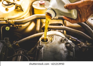 Car mechanic replacing and pouring fresh oil into engine at maintenance repair service station, closeup
