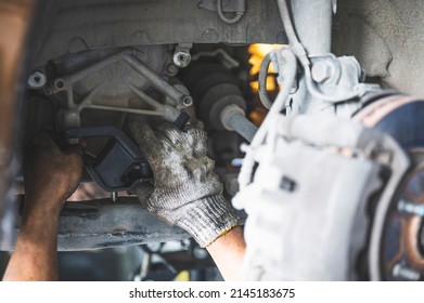 Car mechanic replacing transmission mounts.