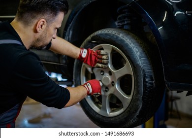 Car Mechanic Replacing Wheel In A Workshop