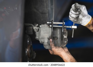 Car mechanic retracting brake pistons on a front brake caliper.