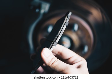 Car mechanic or serviceman checking a disc brake and asbestos brake pads it's a part of car use for stop the car for safety at front wheel this a used old part for change at car garage - Shutterstock ID 1216903762