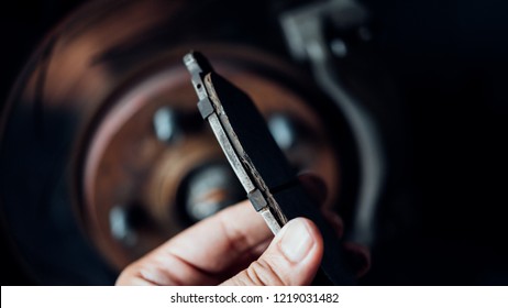 Car mechanic or serviceman checking a disc brake and asbestos brake pads it's a part of car use for stop the car for safety at front wheel this a used old part for change at car garage - Shutterstock ID 1219031482