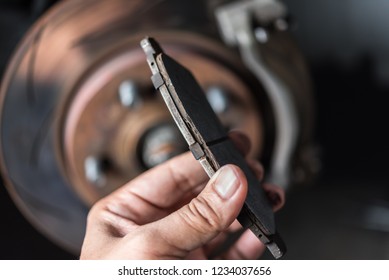 Car mechanic or serviceman checking a disc brake and asbestos brake pads it's a part of car use for stop the car for safety at front wheel this a used old part for change at car garage - Shutterstock ID 1234037656