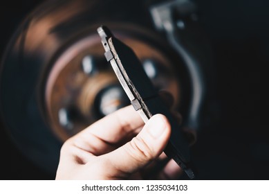 Car mechanic or serviceman checking a disc brake and asbestos brake pads it's a part of car use for stop the car for safety at front wheel this a used old part for change at car garage - Shutterstock ID 1235034103