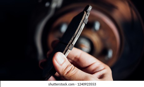 Car mechanic or serviceman checking a disc brake and asbestos brake pads it's a part of car use for stop the car for safety at front wheel this a used old part for change at car garage - Shutterstock ID 1240923553