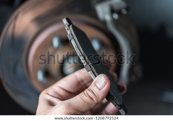 Car\
mechanic or serviceman checking a disc brake and asbestos brake\
pads it\'s a part of car use for stop the car for safety at front\
wheel this a used old part for change at car\
garage
