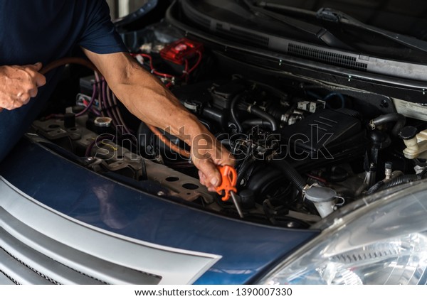 Car mechanic or serviceman cleaning the car engine\
after checking a car engine for fix and repair problem at car\
garage or repair shop